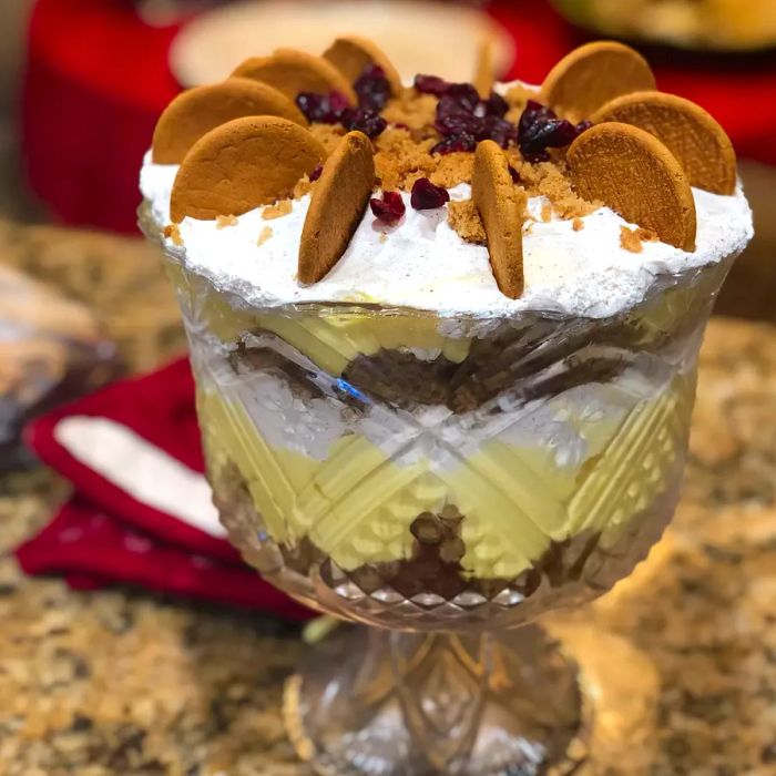 A trifle topped with gingerbread in a glass dish.