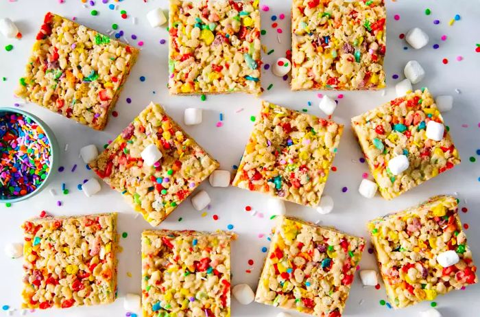 A top-down view of colorful Funfetti Cake Batter Rice Krispies treats, topped with marshmallows and sprinkles scattered across the surface.