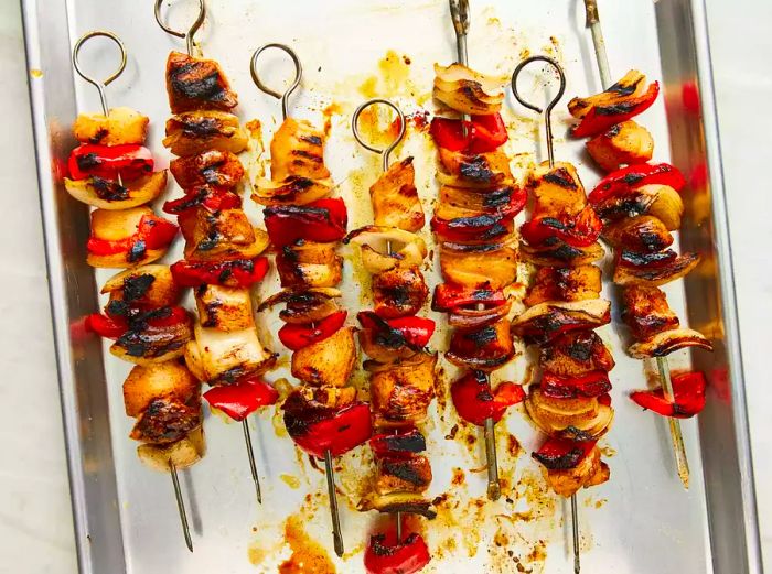 Grilled kabobs, beautifully charred and ready to serve, resting on a baking sheet.