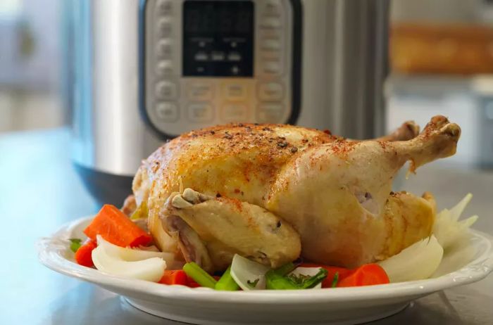 A whole chicken cooked in the Instant Pot resting on a bed of vegetables