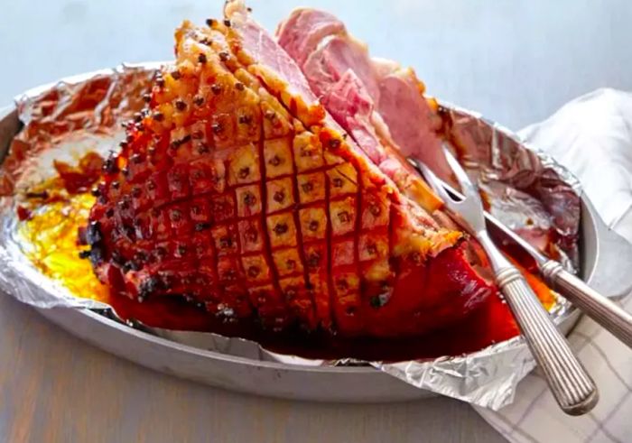 A serving platter with ham studded with cloves