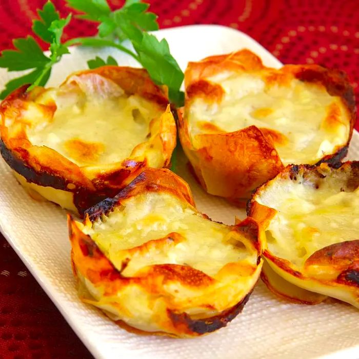 Muffin tin potatoes gratin served on a white dish, garnished with parsley.