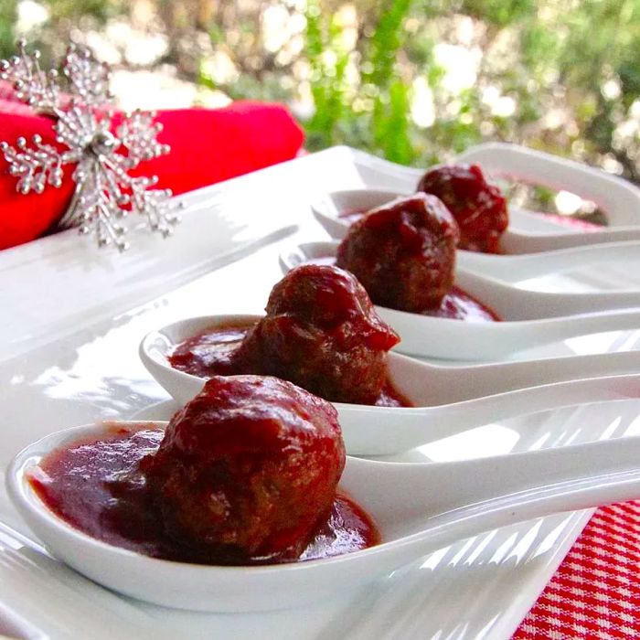 Cocktail meatballs served in white spoons, ready to be enjoyed.