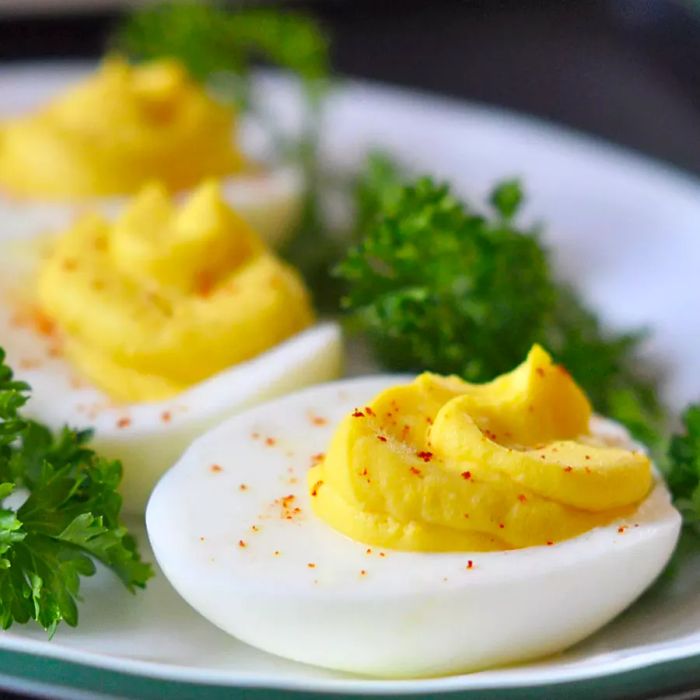 A plate of three deviled eggs, garnished with paprika and parsley