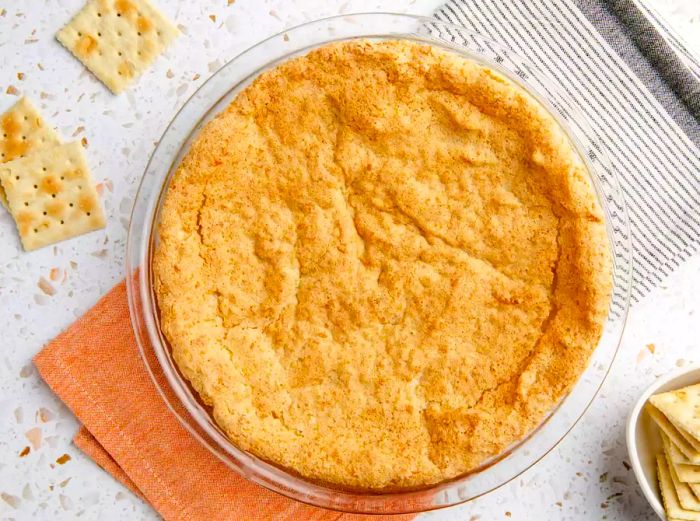 A top-down shot of a puffed-up crust in a glass pie dish.