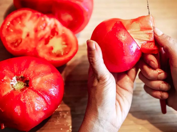 hand holding tomato and peeling with a paring knife