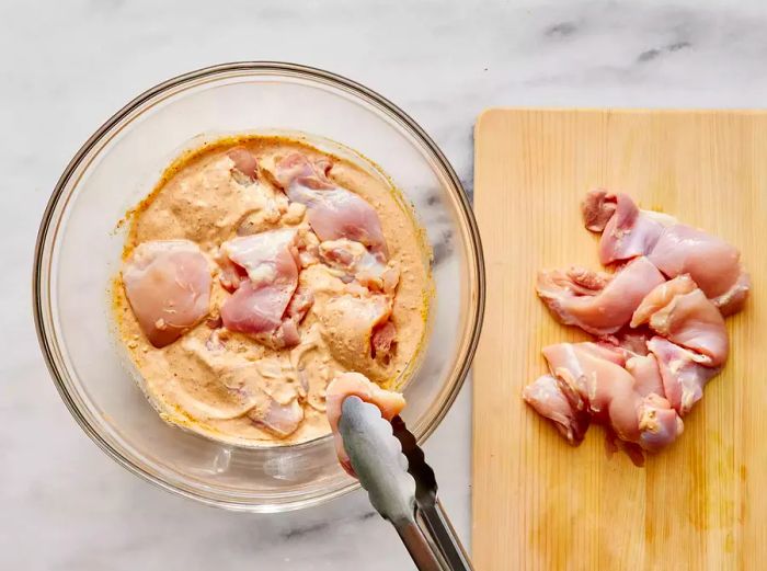 Submerge the chicken thighs into the yogurt marinade.