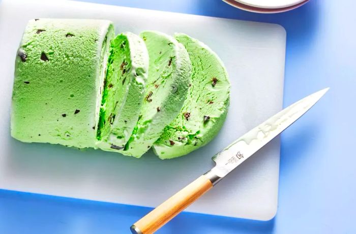 An overhead shot of a block of mint chocolate chip ice cream, sliced into rounds.