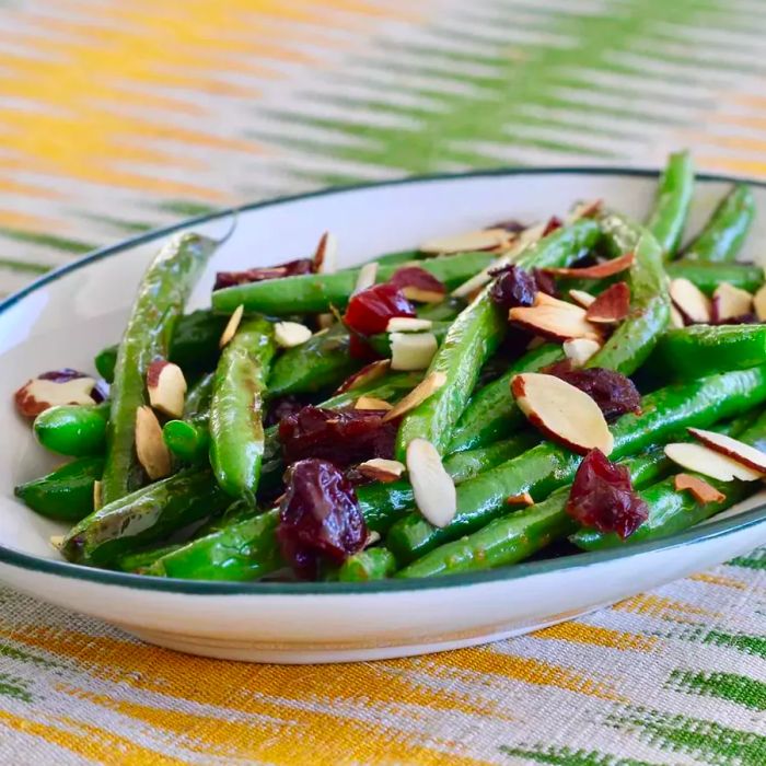 Green beans, almond slivers, and cranberries served in a white dish.