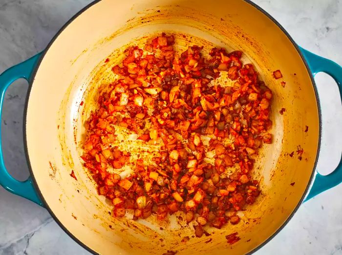 An overhead shot of garlic and onions sautéing in a pot.