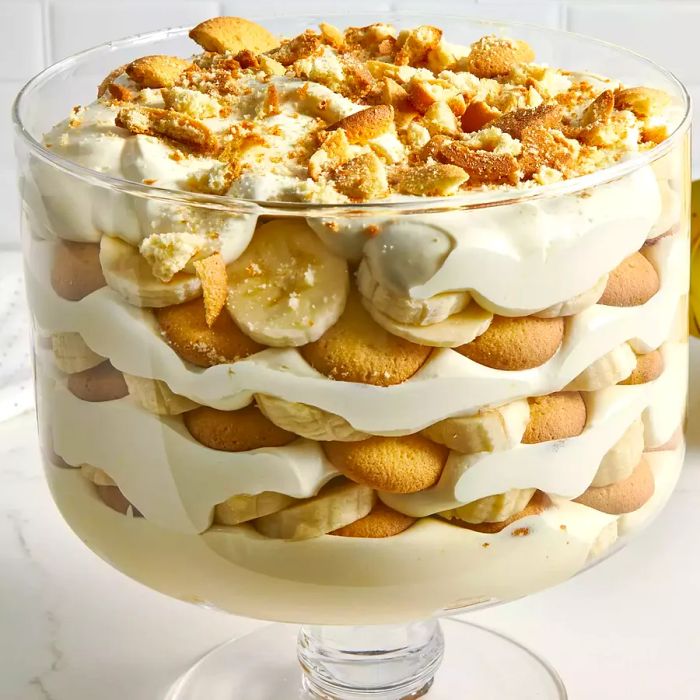 A close-up shot from a low angle showing layers of creamy banana pudding in a trifle dish.