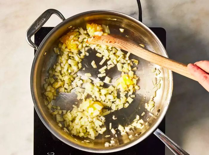 A large skillet with onions being sautéed in ghee