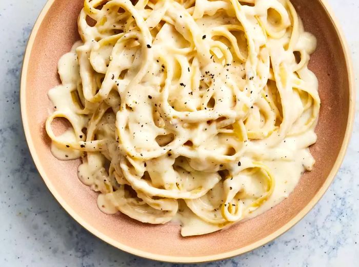 aerial view of a shallow bowl filled with fettuccine noodles and topped with creamy Alfredo sauce