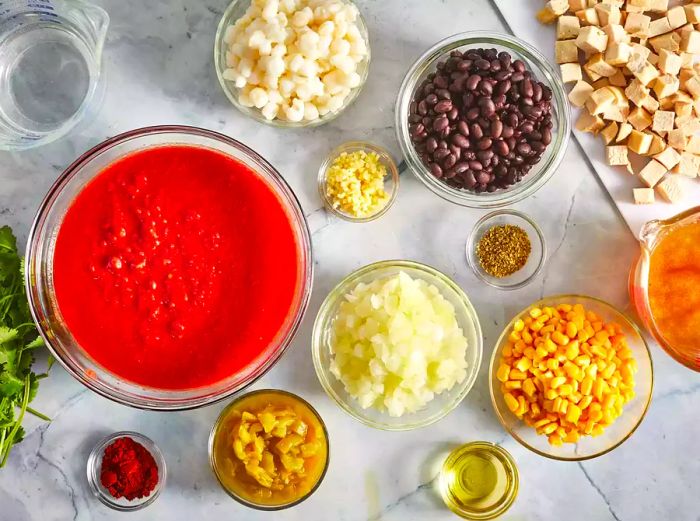 An overhead view of tortilla soup ingredients neatly arranged in bowls and measuring cups.