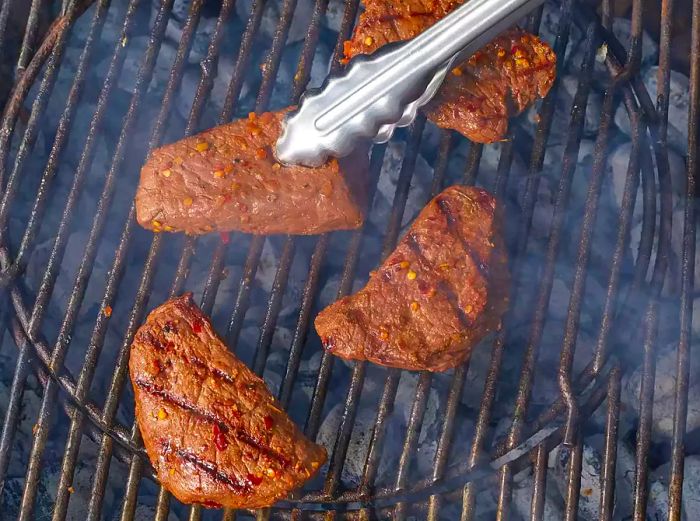 Aerial shot of venison steaks grilling on a charcoal barbecue