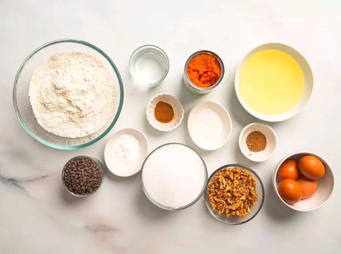 A variety of ingredients in bowls ready to be mixed for chocolate chip pumpkin bread.