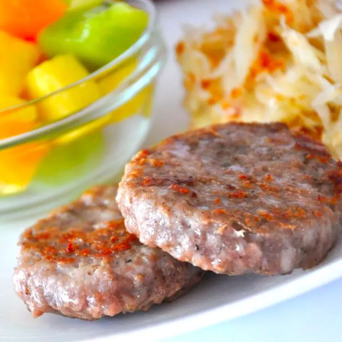 A hearty breakfast sausage served alongside potato hash and fresh fruit