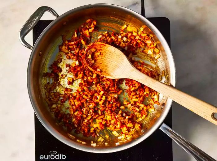 A skillet with chopped onions and garlic being cooked with spices