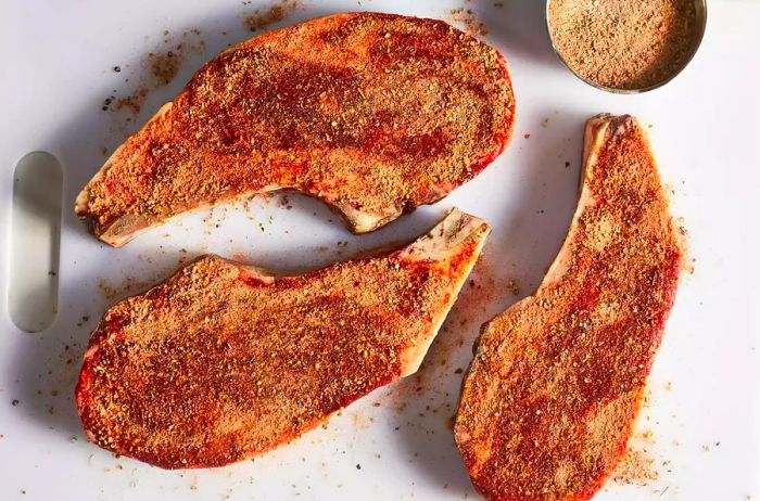 overhead shot of three raw steaks seasoned with a dry rub of herbs and spices