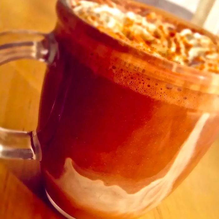 A cup of hot cocoa topped with fluffy whipped cream in a glass mug.