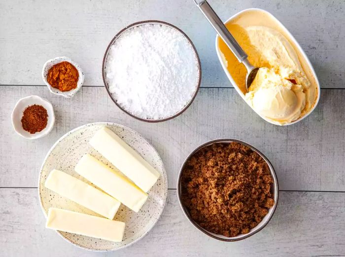 A variety of bowls filled with the necessary ingredients to prepare the hot buttered rum batter.