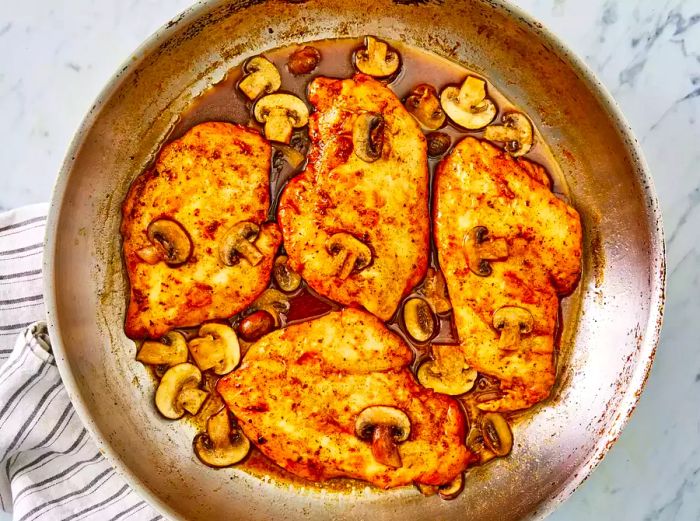 Close-up of Chicken Marsala with Mushrooms and Sauce in a Metal Skillet