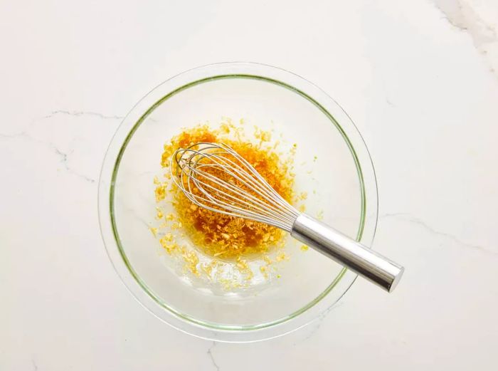 A mixture of canola oil, lemongrass, lemon juice, soy sauce, brown sugar, garlic, and fish sauce being whisked in a bowl.