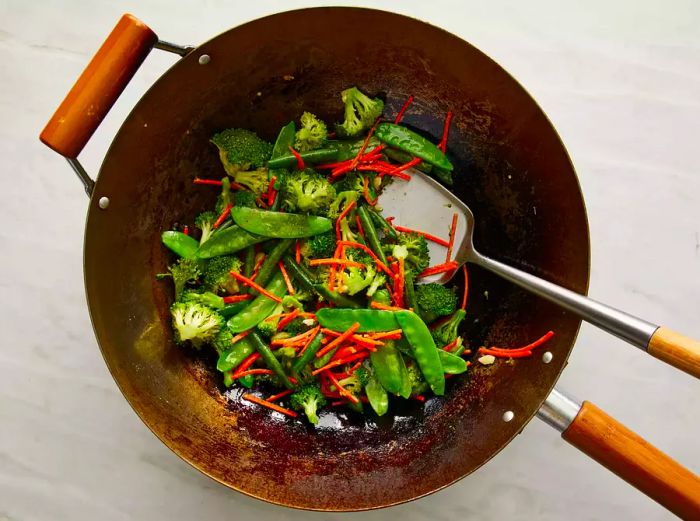 A top-down view of vegetables frying in a wok.