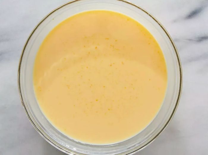 A top-down view showing milk and condensed soup whisked together in a bowl until smooth.