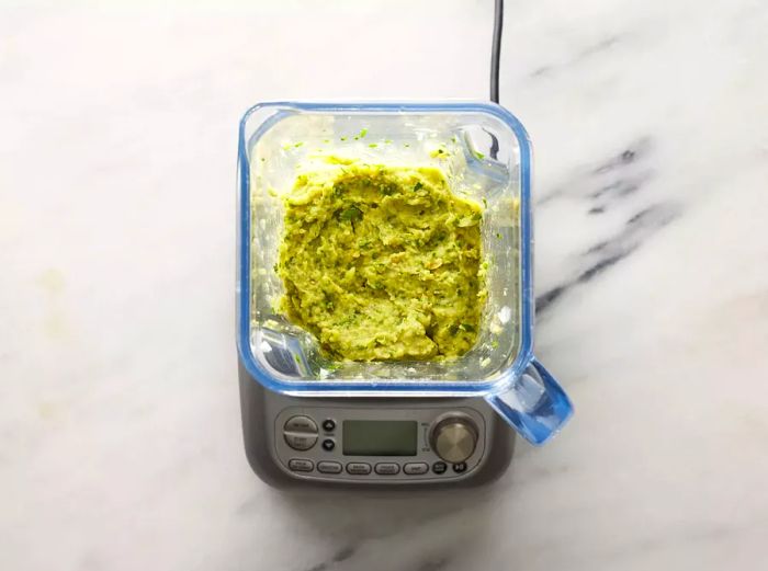 Aerial view of mashed chickpeas, onions, parsley, and garlic blended together in a processor