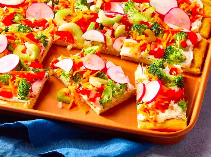 A baking sheet filled with square slices of veggie pizza