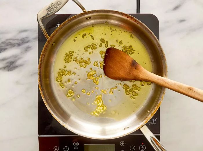 A pan with chopped garlic cooking in hot oil