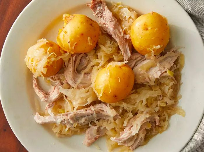 A top-down view of a plate filled with slow cooker pork and sauerkraut.