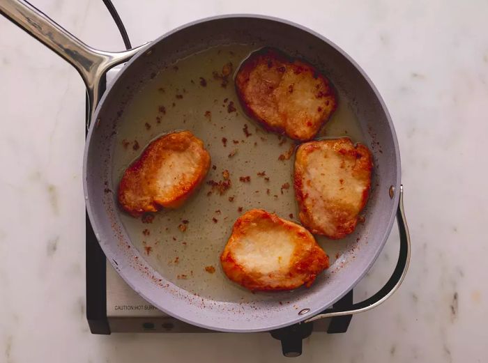 Pork chops in a frying pan.