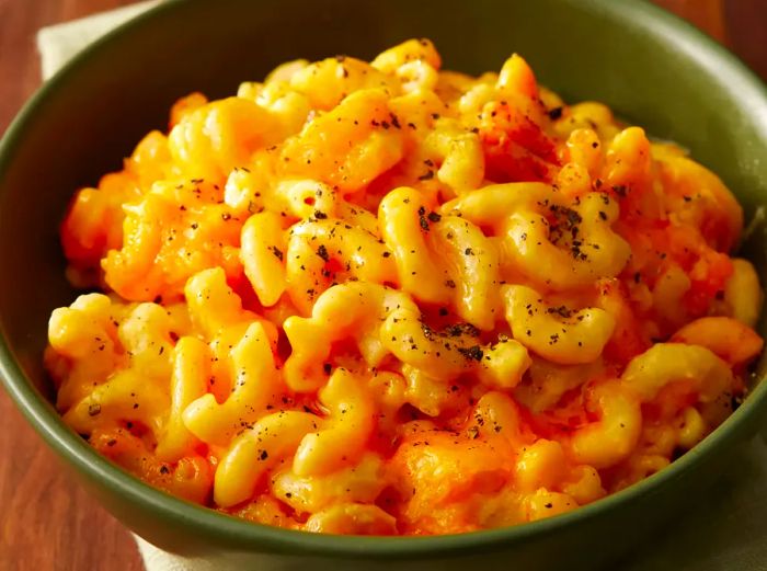 A high-angle view of a green bowl filled with slow-cooked mac and cheese.