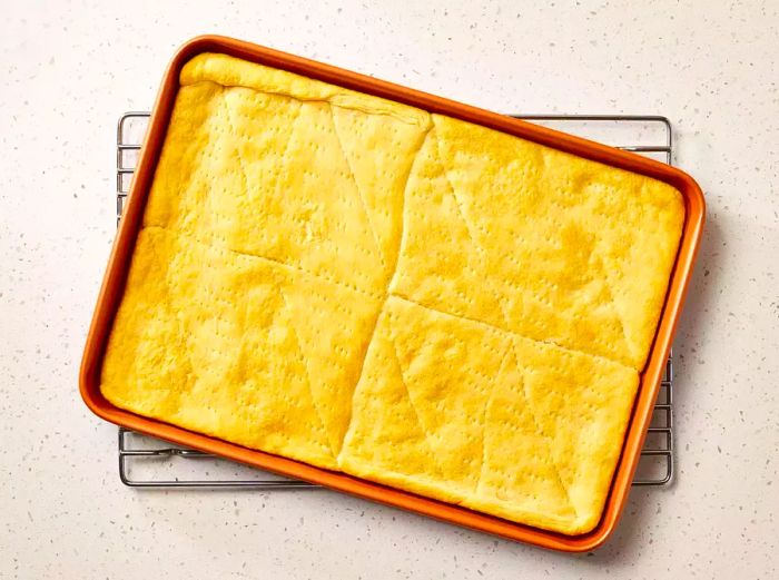 A jelly roll pan with baked crescent dough, resting on a wire rack to cool.