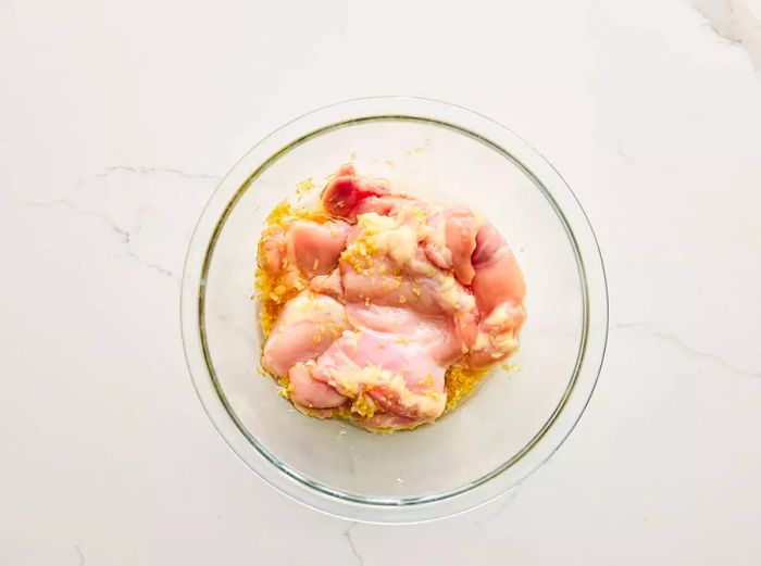 A bowl containing raw chicken coated in the fragrant lemongrass marinade.