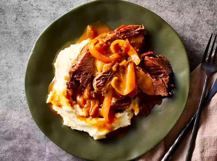 A plate of slow-cooked venison roast, paired with creamy mashed potatoes.