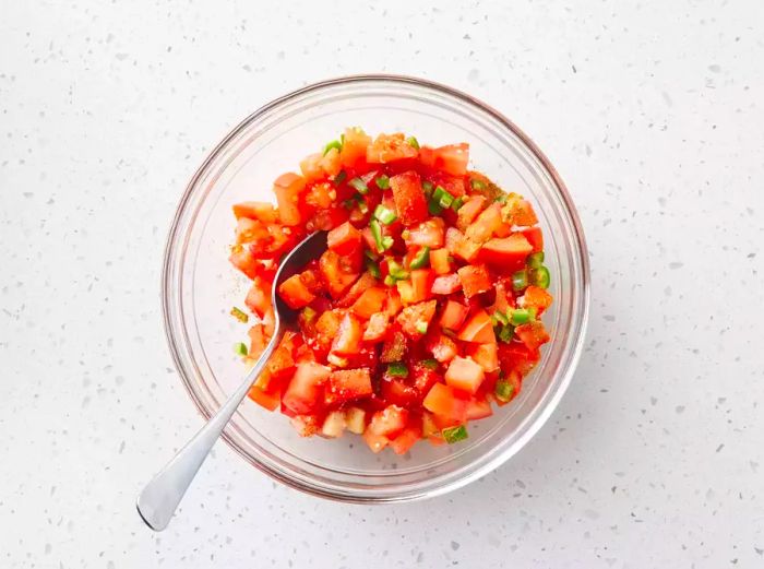 A mixture of tomatoes, chile peppers, and spices blended together in a bowl.