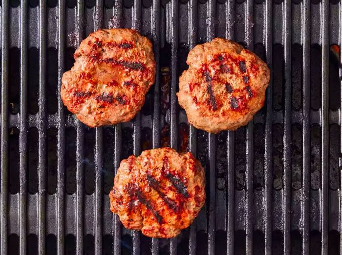 Grilled hamburger patties sizzling on the grill