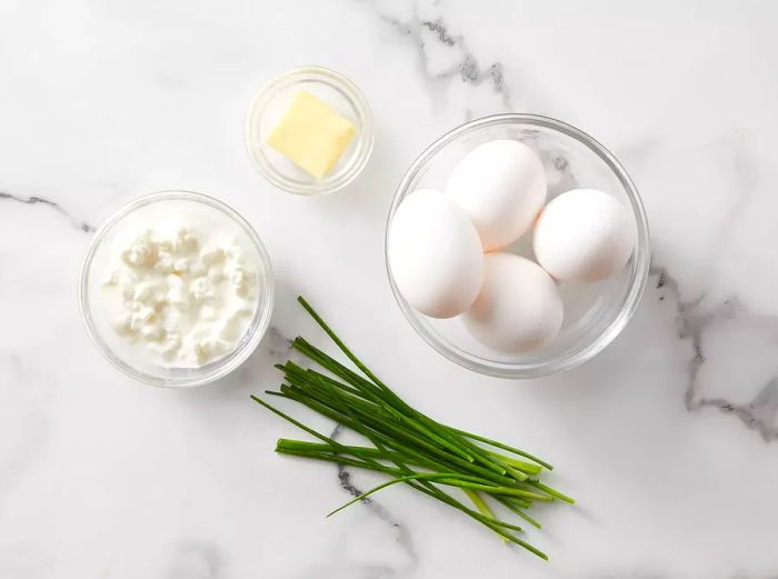 All the ingredients are ready to make creamy scrambled eggs with cottage cheese.