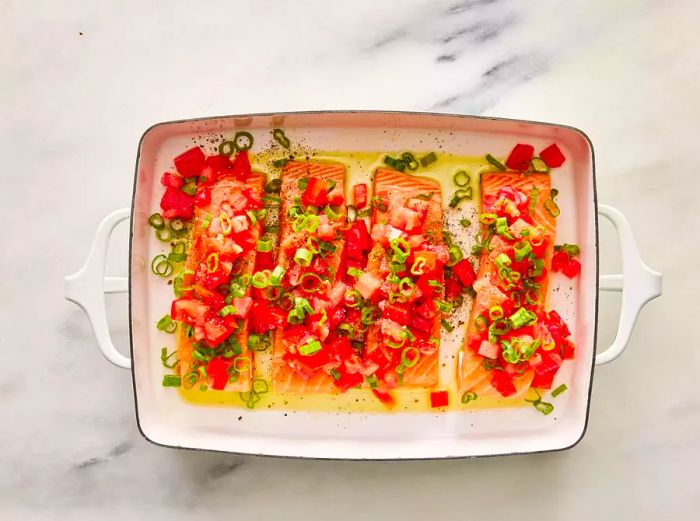 Salmon garnished with diced tomatoes, green onions, and seasoned with salt and pepper.