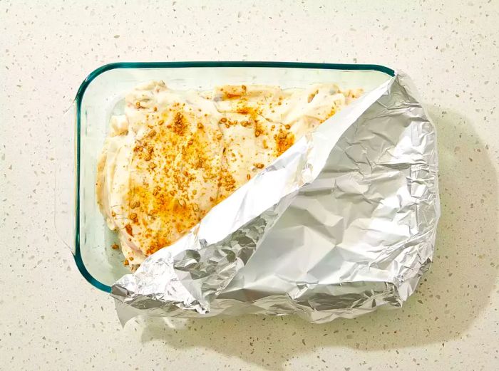 Water and crumbled bouillon cubes are added to the dish, then covered with aluminum foil.