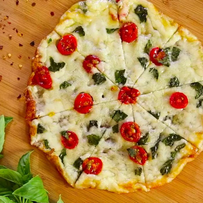 An overhead shot of a Cheesy-Crust Skillet Pizza topped with tomatoes and basil