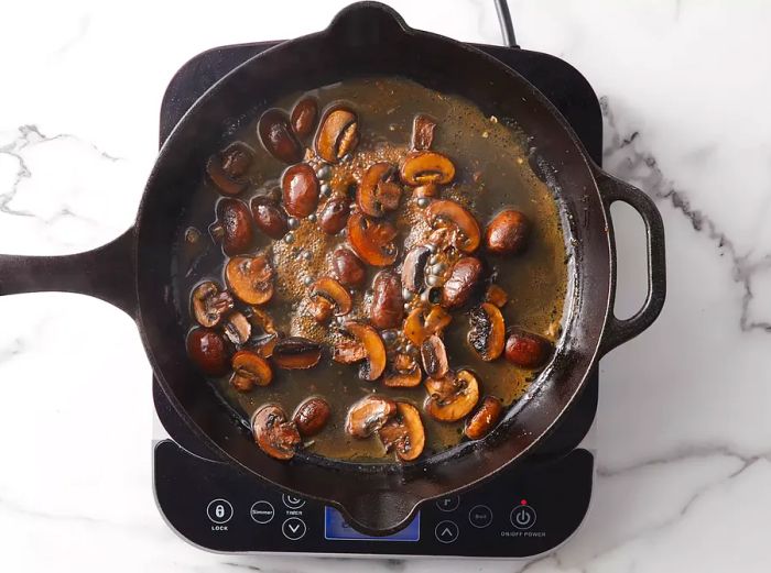 Water is added to the mushrooms as you scrape up the browned bits from the skillet.