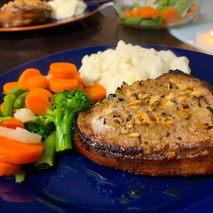 Bacon-wrapped filet mignon served with mashed potatoes and sautéed vegetables