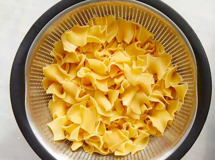 A top-down view of cooked pasta resting in a colander.