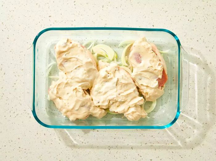 Onions placed at the bottom of the baking dish, topped with pork chops and smothered in creamy mushroom soup.