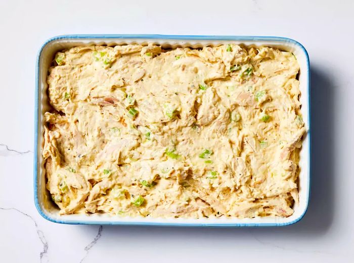 A baking dish filled with the creamy chicken soup mixture spread evenly across the bottom