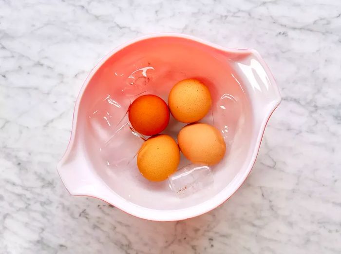 A small bowl with four eggs submerged in ice water